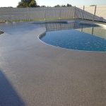 A concrete swimming pool deck area with an acrylic chip coating.